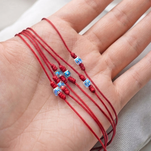 LUCKY CHARM. SET 6 PULSERAS CON OJOS CUADRADOS Y CORDONES ROJOS