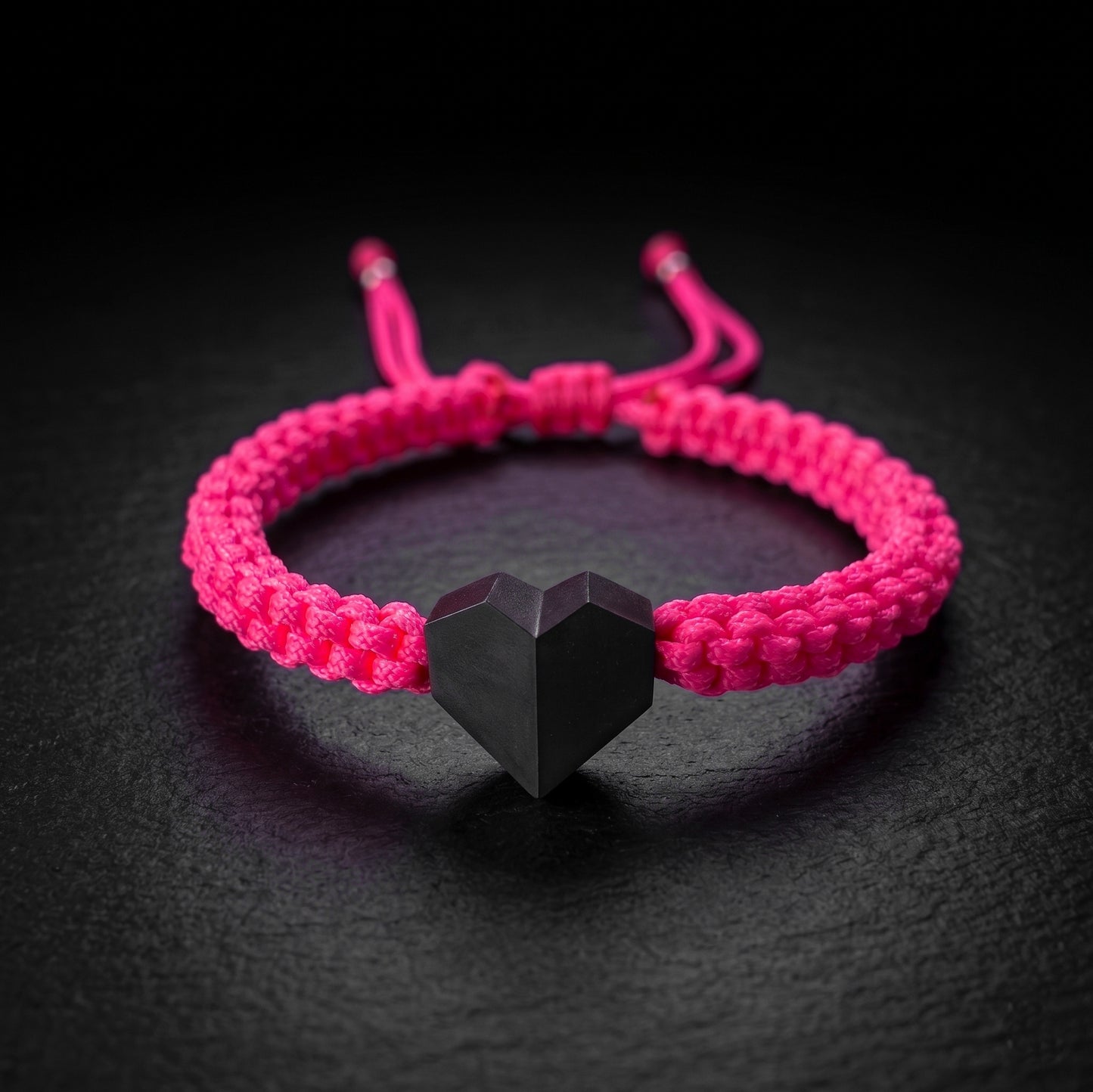 TINY LOVE. PULSERA CON CORAZON NEGRO Y CORDON TRENZADO ROSA NEON
